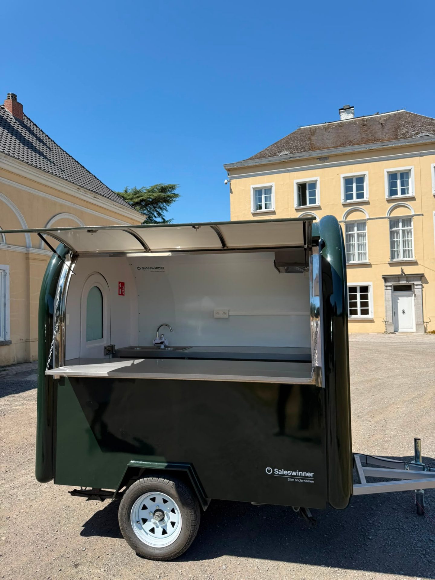 Zijaanzicht van de foodtruck met spoelbak en volledig geopende luifel